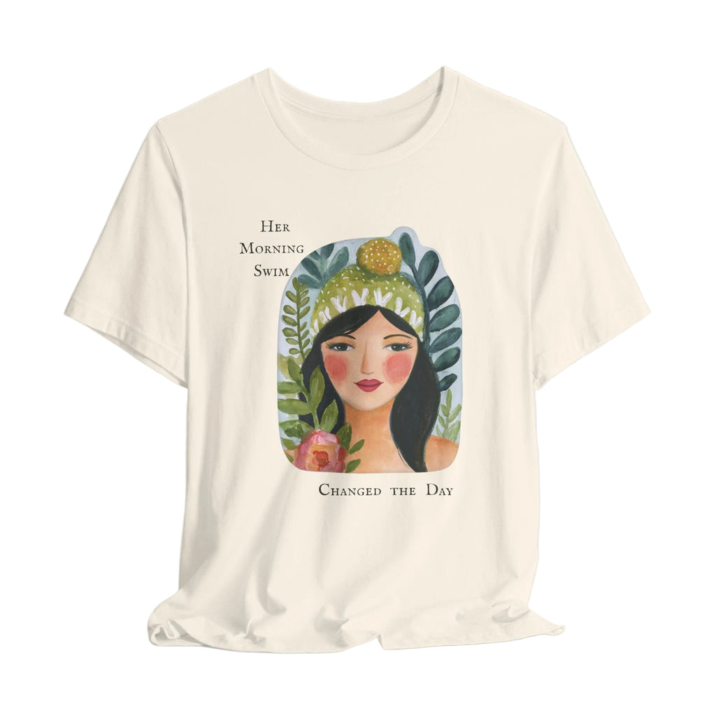 Beige t-shirt with a graphic of a woman's face surrounded by plants and text on a light gray background