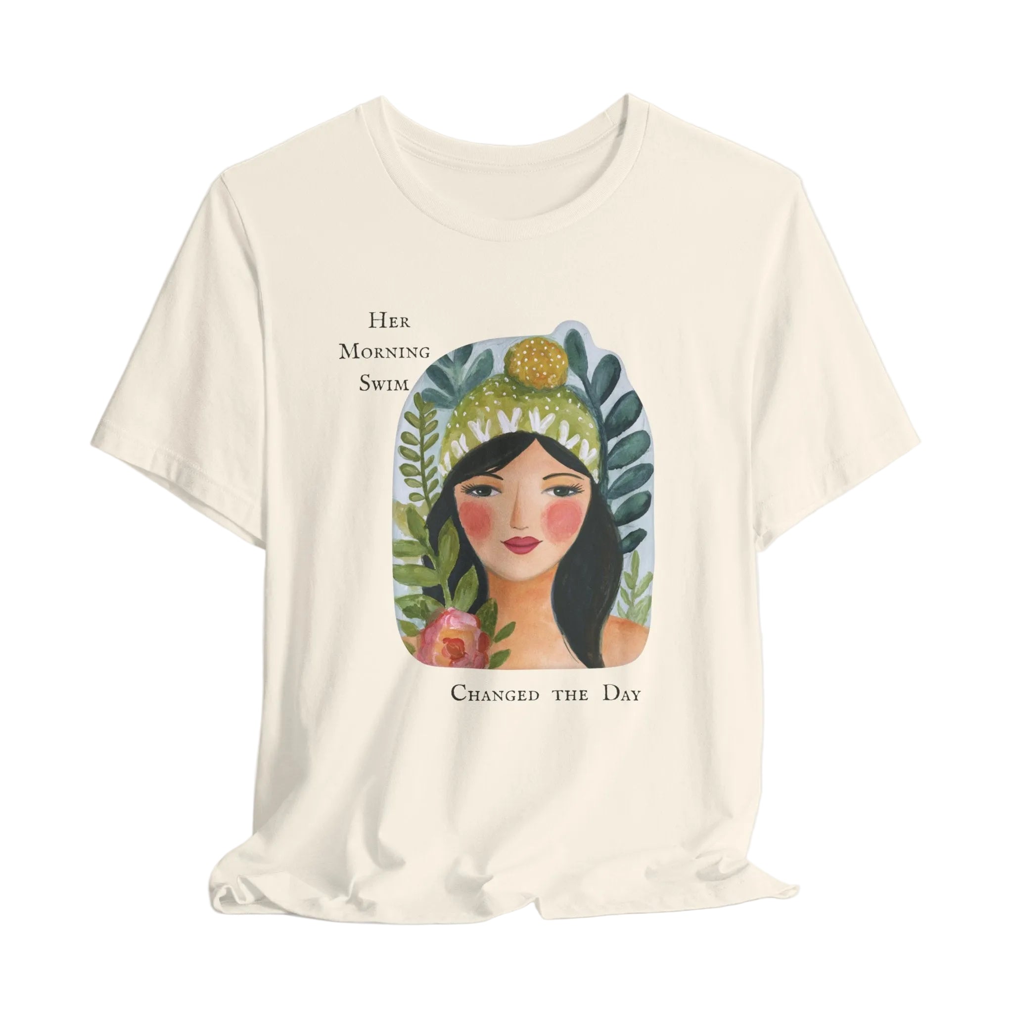 Beige t-shirt with a graphic of a woman's face surrounded by plants and text on a light gray background